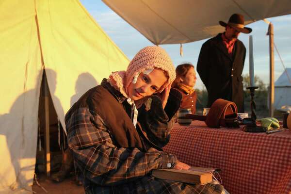 Pecos Hopkins, 11, sits down to read a novel as she camps with family at Horse Head Crossing in Pecos County on Oct. 31, 2020. They are volunteers with the Fort Griffin Living History Association.