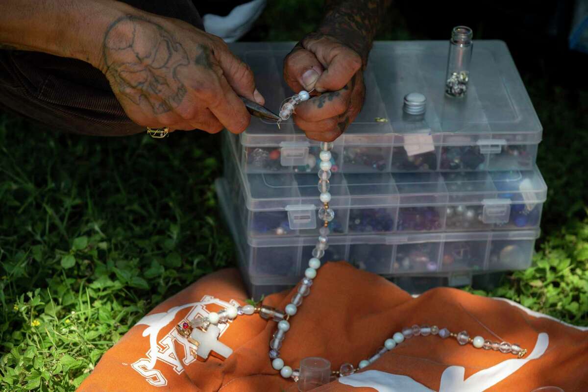A homeless man makes beaded rosaries in the shade at San Pedro Springs Park in June. People experiencing homelessness are just trying to get through life carrying enormous burdens, and they deserve our compassion.