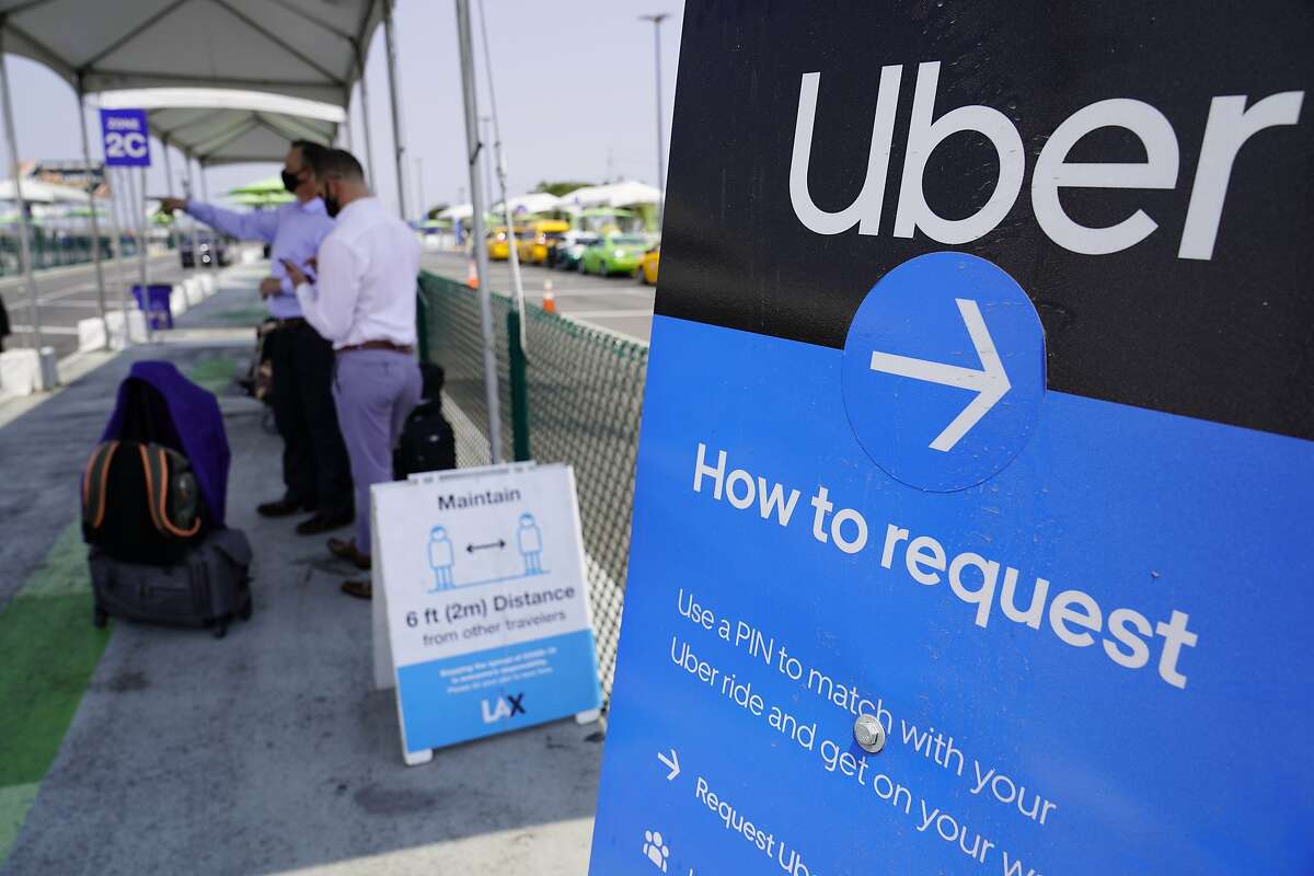Travelers request an Uber ride at Los Angeles International Airport — Uber and Lyft drivers remain contractors under Proposition 22, but that could be changed by the federal government.