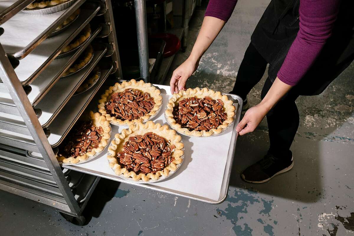 Julie Tran places Bourbon Pecan pies on a rack to cool while working at Three Babes Bakeshop.