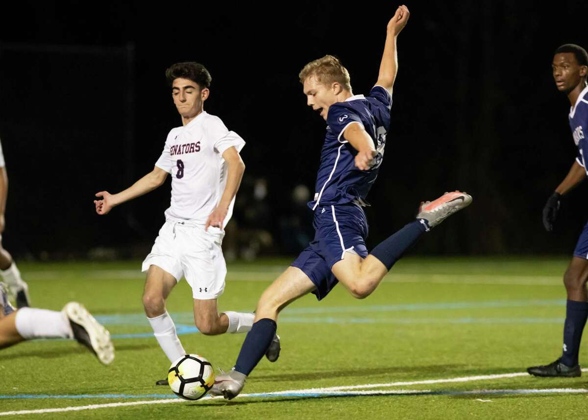Wilton’s Oliver Dahlen looks to take a shot while McMahon’s Evangelos Mallios (8) defends in Friday night’s FCIAC Central Region title game.