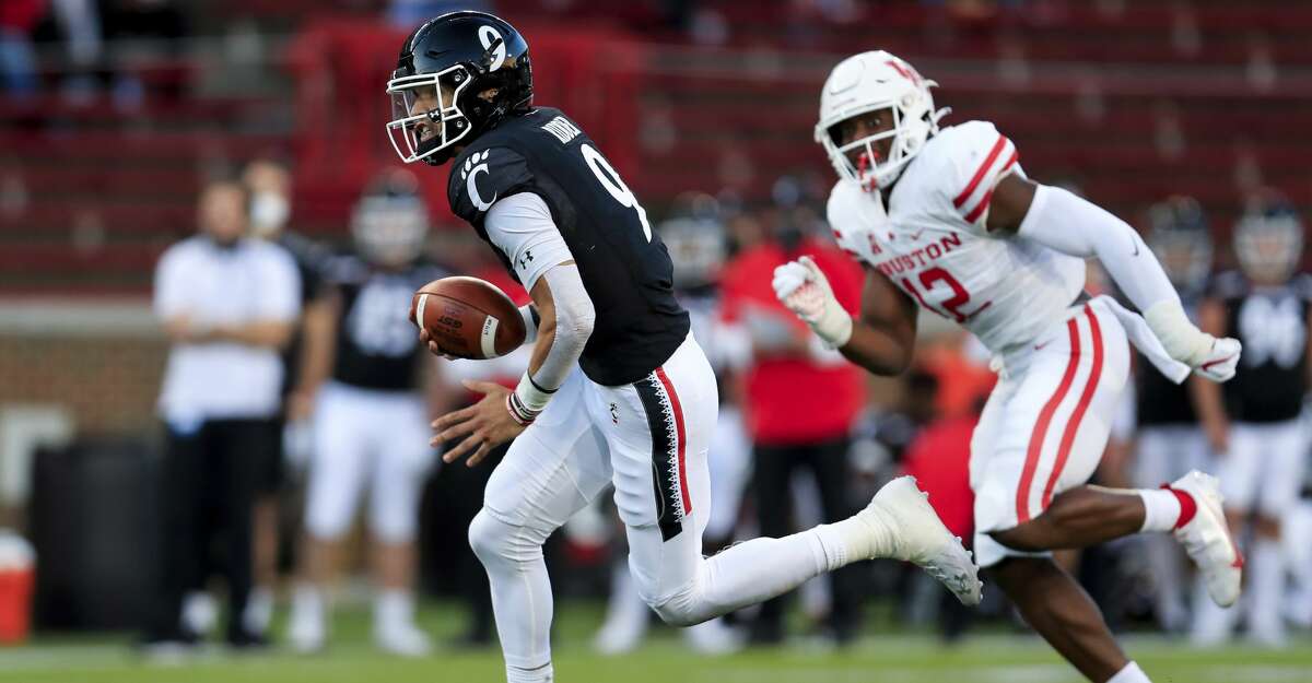 Cincinnati quarterback Desmond Ridder, left, carries the ball for a touchdown during the first half of an NCAA college football game against Houston, Saturday, Nov. 7, 2020, in Cincinnati. (AP Photo/Aaron Doster)