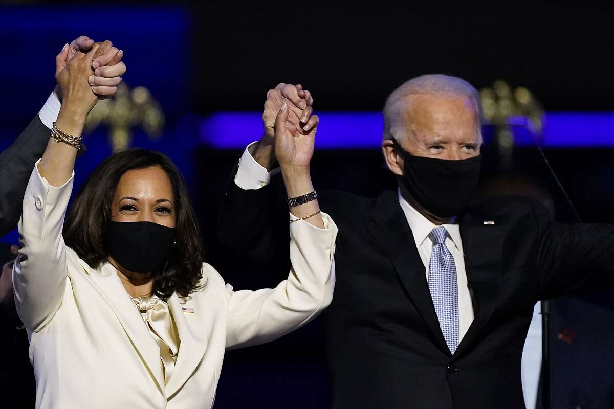 Vice President-elect Kamala Harris holds hands with President-elect Joe Biden and her husband Doug Emhoff as they celebrate Saturday, Nov. 7, 2020, in Wilmington, Del. (AP Photo/Andrew Harnik)
