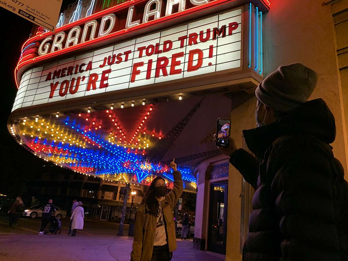 Adrienne Lam has her photo taken by Andrew Lee, both of Oakland, underneath the marquee at Grand Lake Theater that reads, “America just told Trump, ‘You’re Fired,’” on Saturday, November 7, 2020, in Oakland, Calif. “I’ve been crying all day. Just tears of happiness, relief and joy,” Lam said. “It’s the first time we’ve heard a leader in a long time.” (Yalonda M. James / The Chronicle)