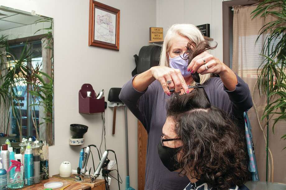 Stylist Angela Hadden measures and cuts 15-year-old Cordin Ledger’s hair Saturday at Pizzazz Salon in Jacksonville. Ledger has been growing his hair the past year and decided to donate it to a charity for children who have suffered hair loss from cancer or other conditions. Photo: Darren Iozia | Journal-Courier / Jacksonville Journal-Courier