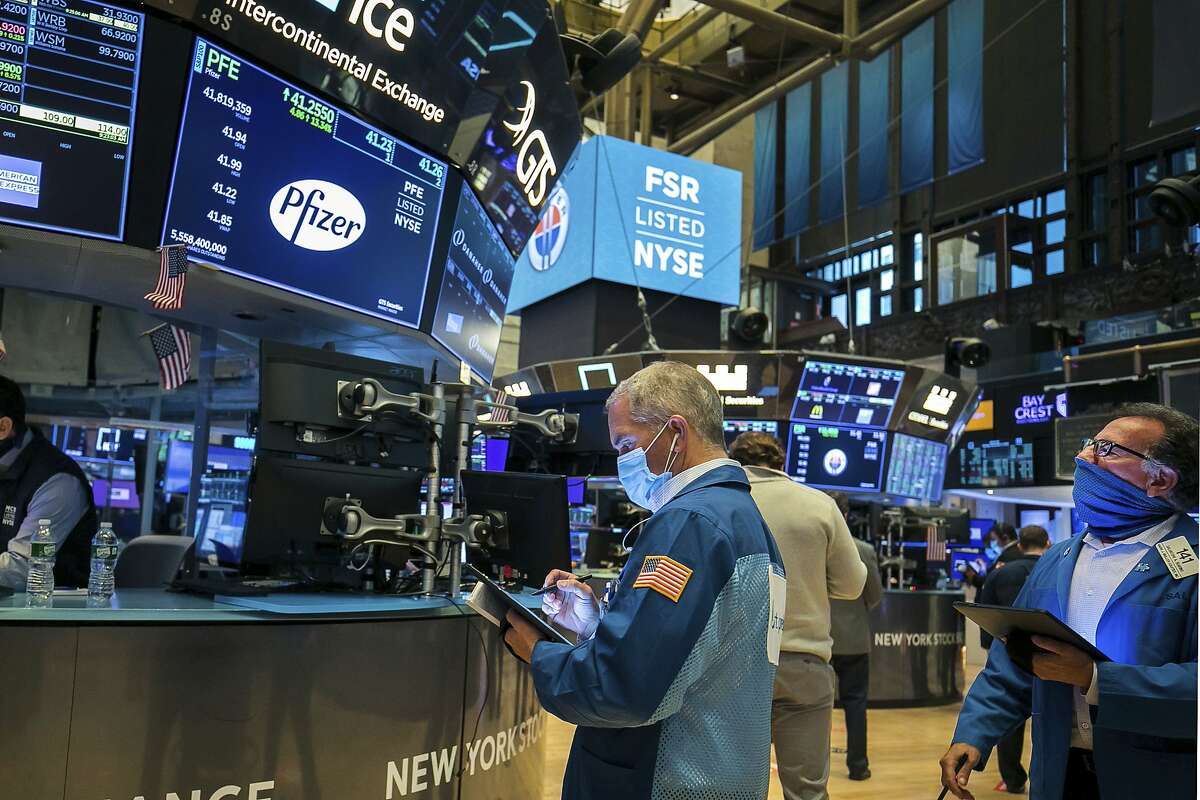 In this photo provided by the New York Stock Exchange, traders Timothy Nick, center, and Sal Suarino, right, work on the floor, Monday Nov. 9, 2020. Stocks around the world are surging Monday, sending Wall Street back to record heights, on a burst of hope following encouraging data for a potential COVID-19 vaccine from Pfizer. (Courtney Crow/New York Stock Exchange via AP)