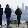 In this file photo, a family dressed for cold weather walks down a path in front of the San Francisco skyline near Sausalito, California.