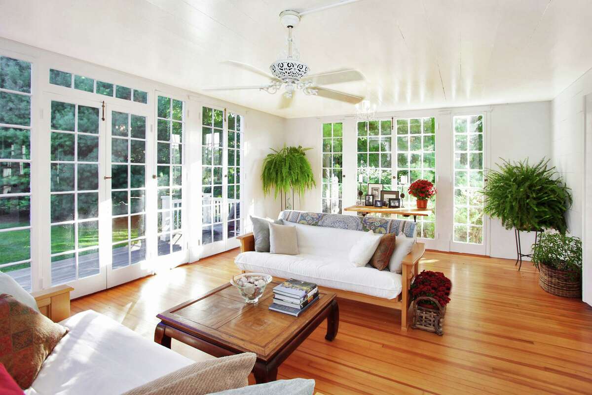 The spacious sun room features nearly floor-to-ceiling windows and doors to the wrap-around deck and a hot tub. There are four bedrooms with wide-plank hardwood flooring on the second floor. There is also a den or family room with the home's third fireplace. The third floor office has exposed posts and beams and a wall of built-in drawers.