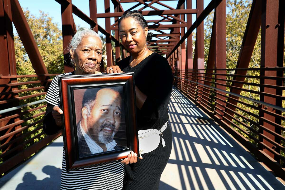 Catherine Lawson (links) trägt ein Bild ihres Mannes Jerry Lawson mit ihrer Tochter Karen Lawson (rechts) auf einer Brücke über den Guadalupe River am Donnerstag, 5. 5, 2020, in San Jose, Kalifornien.