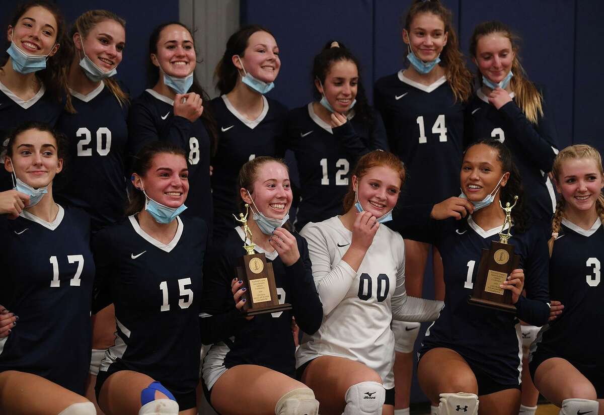 Staples teammates pull down their masks for a group photo after their victory over Ridgefield in the FCIAC Central volleyball championship match Tuesday.
