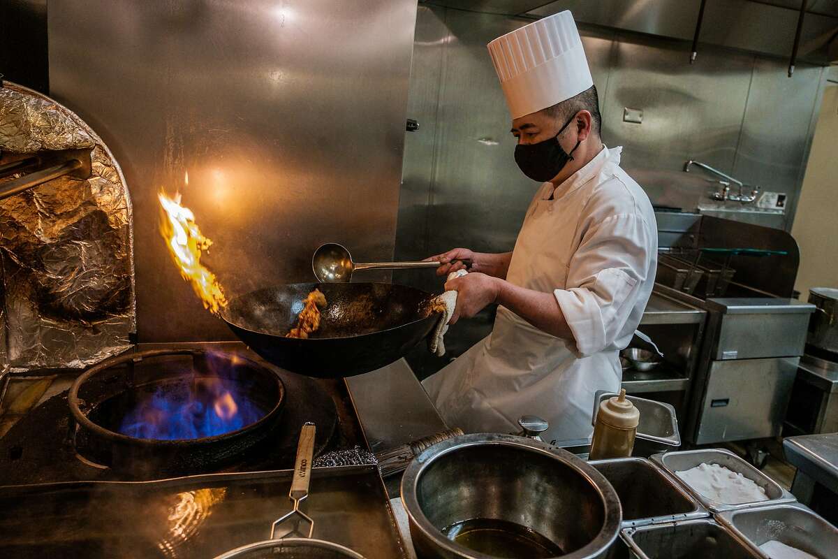 Chef Chao Hua Lei prepares a dish in a wok on a gas stove at Yank Sing. The S.F. supervisors’ move to ban natural gas use in new buildings provides for a waiver for restaurant spaces.