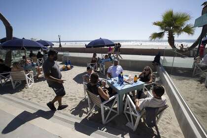 Diners sit at outside tables at the Beach House Grill in San Diego in May. San Diego County is one of three of California's largest counties among 10 statewide that regressed on reopening businesses and other activities amid a resurgence in coronavirus cases, state officials said, while San Francisco imposed new restrictions including a ban on indoor dining in a bid to slow the spread of the virus there.