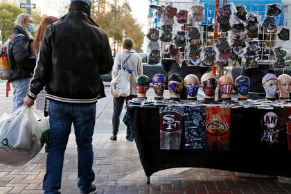 A vendor’s table is filled with face coverings at Fourth and Market streets in San Francisco, which is the only large metro area in California in the yellow “minimal” coronavirus reopening tier.