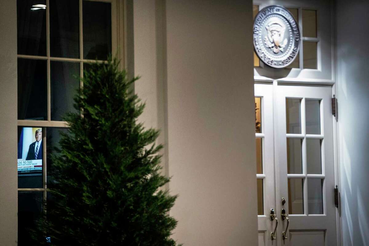 A television is seen through a window near the entrance to the West Wing of the White House on Tuesday night. President Trump's sole public event this week was a wreath-laying at a Veterans Day ceremony.