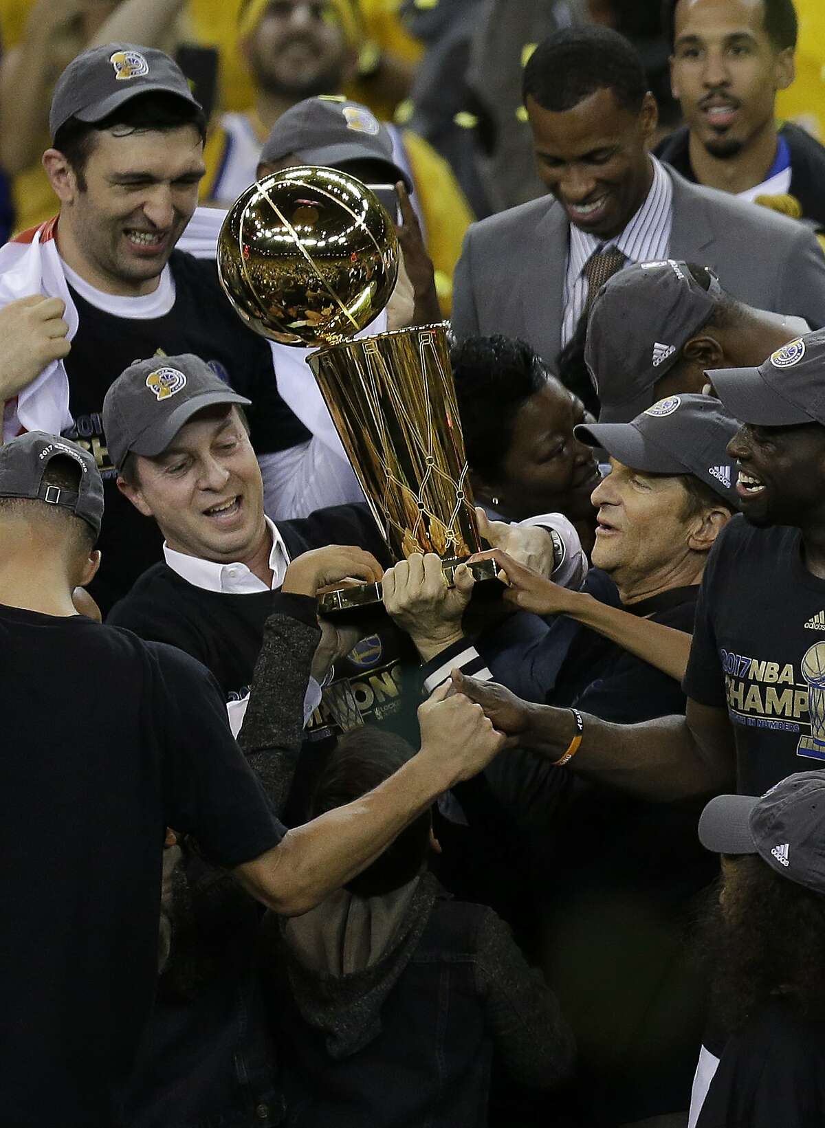 Golden State Warriors owners Joe Lacob, center left, and Peter Guber, center right, hold up the Larry O'Brien NBA Championship Trophy after Game 5 of basketball's NBA Finals between the Warriors and the Cleveland Cavaliers in Oakland, Calif., Monday, June 12, 2017. The Warriors won 129-120 to win the NBA championship.. (AP Photo/Ben Margot)