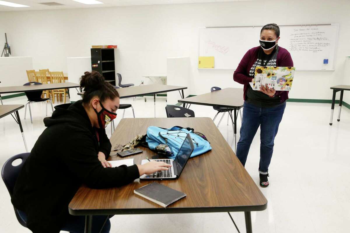 Art teacher Erica That, 44, right, works with senior Deja Hartfield at Holmes High School on Friday. State leaders decided to base funding for the first half of the school on pre-pandemic enrollment numbers. The grace period expires in January and superintendents worry that enrollment declines will cut into resources needed to help higher numbers of students, mostly online learners, who are failing their classes.