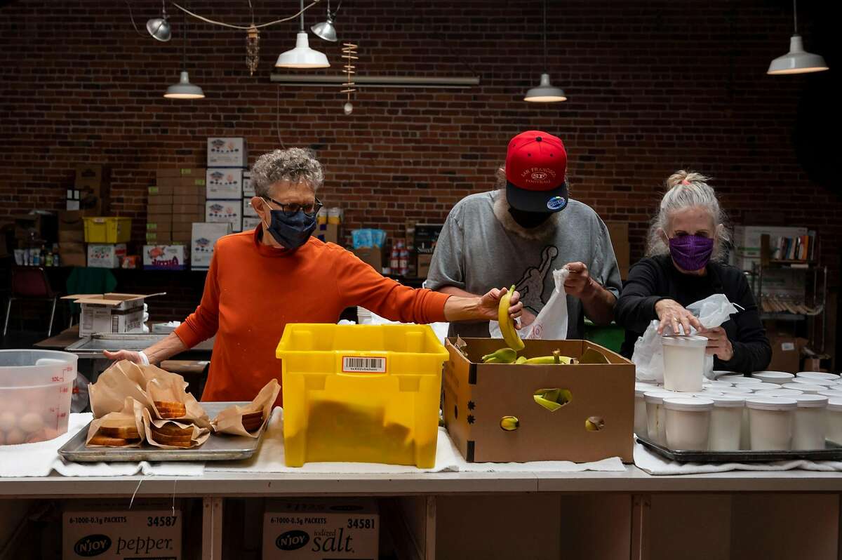 Martin de Porres House of Hospitality Director Mim Locke, Jeff Leggett and Patti Toomey assemble bagged meals for guests in S.F. Traditionally, 200 volunteers prepare the Thanksgiving dinner; this year, it’s eight.
