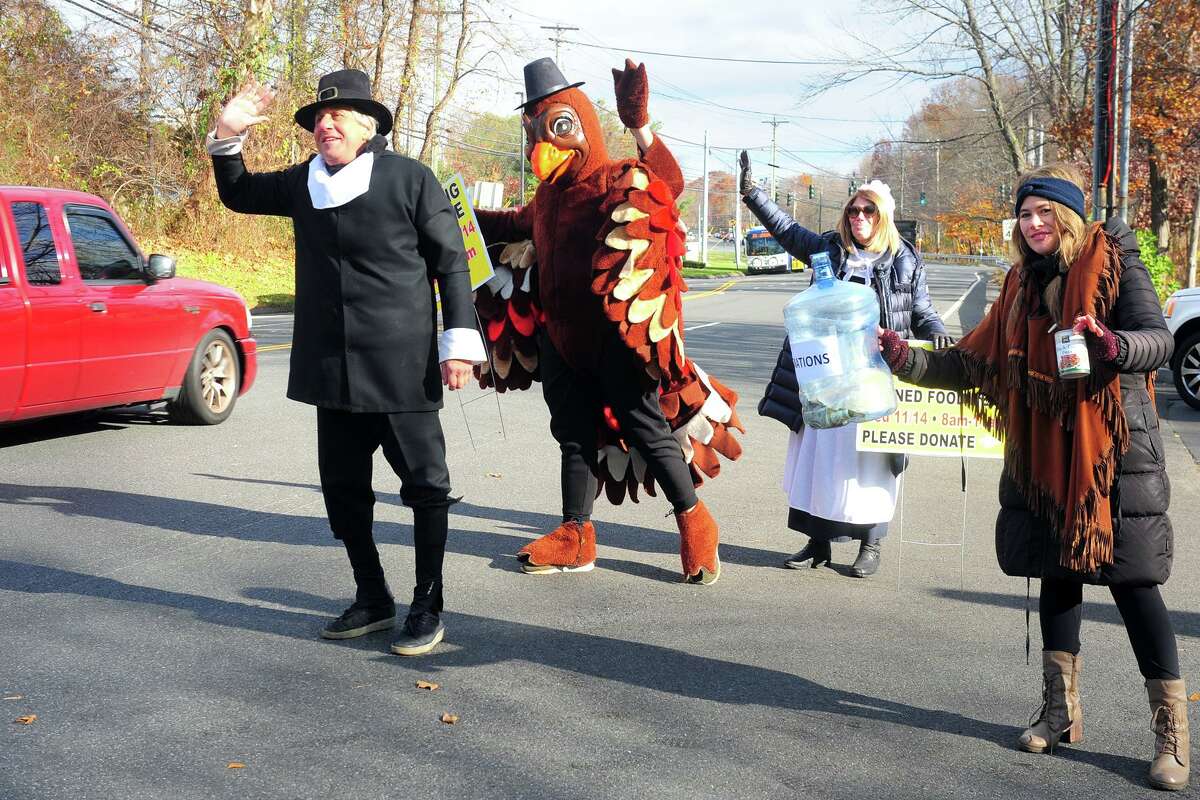 Dressed as a pilgrim, Dr. Bruce Sofferman of Smile Dental Center, left, is joined by turkey Brian Tamburrino and Sofferman’s wife, Deborah, and daughter Sophia as flag down drivers on Bridgeport Avenue during their annual turkey and food collection in Shelton, Conn. Nov. 14, 2018. This is the 32nd year the dentist and family have dressed up in Thanksgiving costumes as they receive donations to be distributed by the Spooner House.