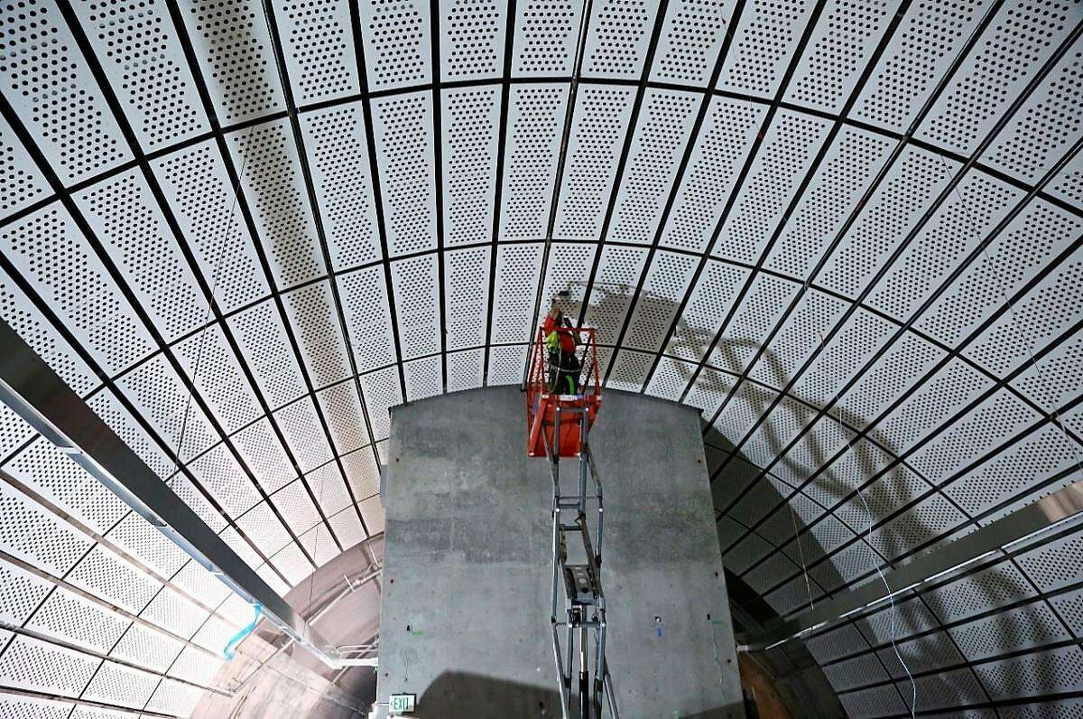 Workers install decorative panels in the Chinatown/Rose Pak Central Subway station.