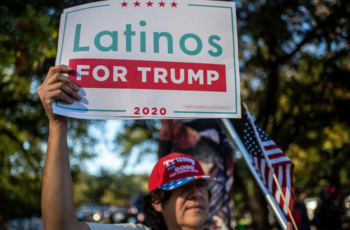 A man holds up a "Latinos for Trump" sign at a protest after Joe Biden won the 2020 presidential election in Austin, Texas on November 7, 2020. (Photo by Sergio FLORES / AFP)