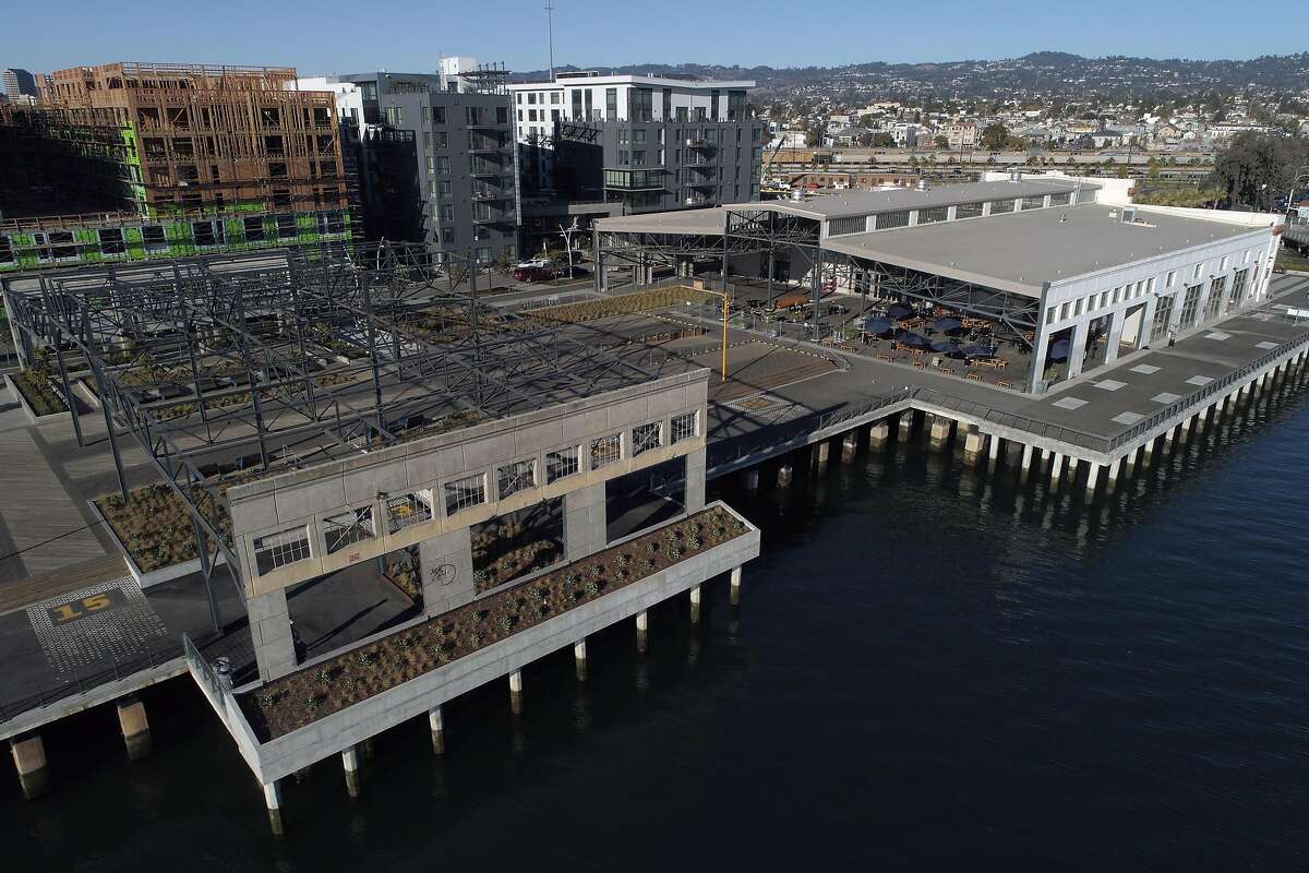 An aerial view of the eastern half of Township Commons, a 4.5-acre park that includes remnants of the shipping terminal that once filled the wharf along the Oakland Estuary. In the background is new housing that marks the initial phase of Brooklyn Basin in Oakland. Township Commons is the 65-acre project’s first public space.