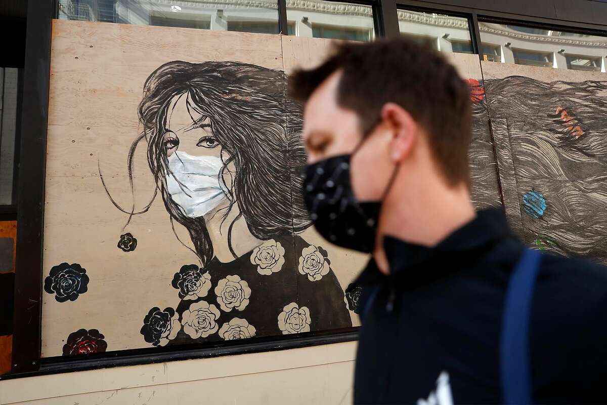 A masked pedestrian passes a mural by Farnaz Zabetian on the Powell Street Walgreen's in San Francisco, Calif., on Thursday, November 12, 2020. California is expected to hit 1 million COVID cases on Thursday as the pandemic continues practically unabated across the country.