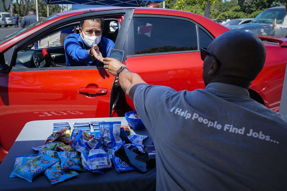 In this Wednesday, May 6, 2020, photo, Brandon Earl, right, helps David Lenus, a job seeker, fill out an application at a drive up job fair for Allied Universal during the coronavirus pandemic, in Gardena, Calif.