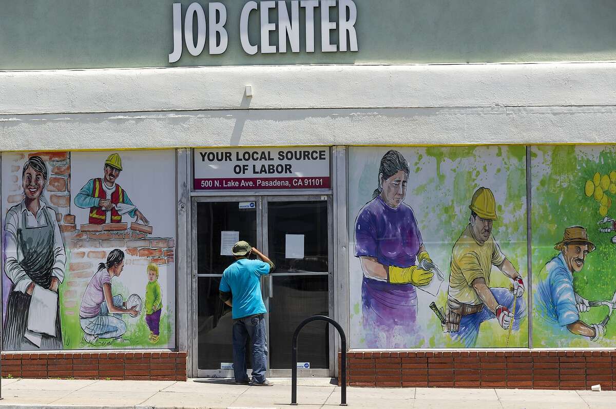 In this May 7, 2020 file photo, a person looks inside the closed doors of the Pasadena Community Job Center in Pasadena, Calif., during the coronavirus outbreak. California's unemployment rate continued to climb in May, reaching 16.3% as businesses continued to lay people off because of a state-at-home order aimed at slowing the spread of the coronavirus that has wrecked the state's economy.