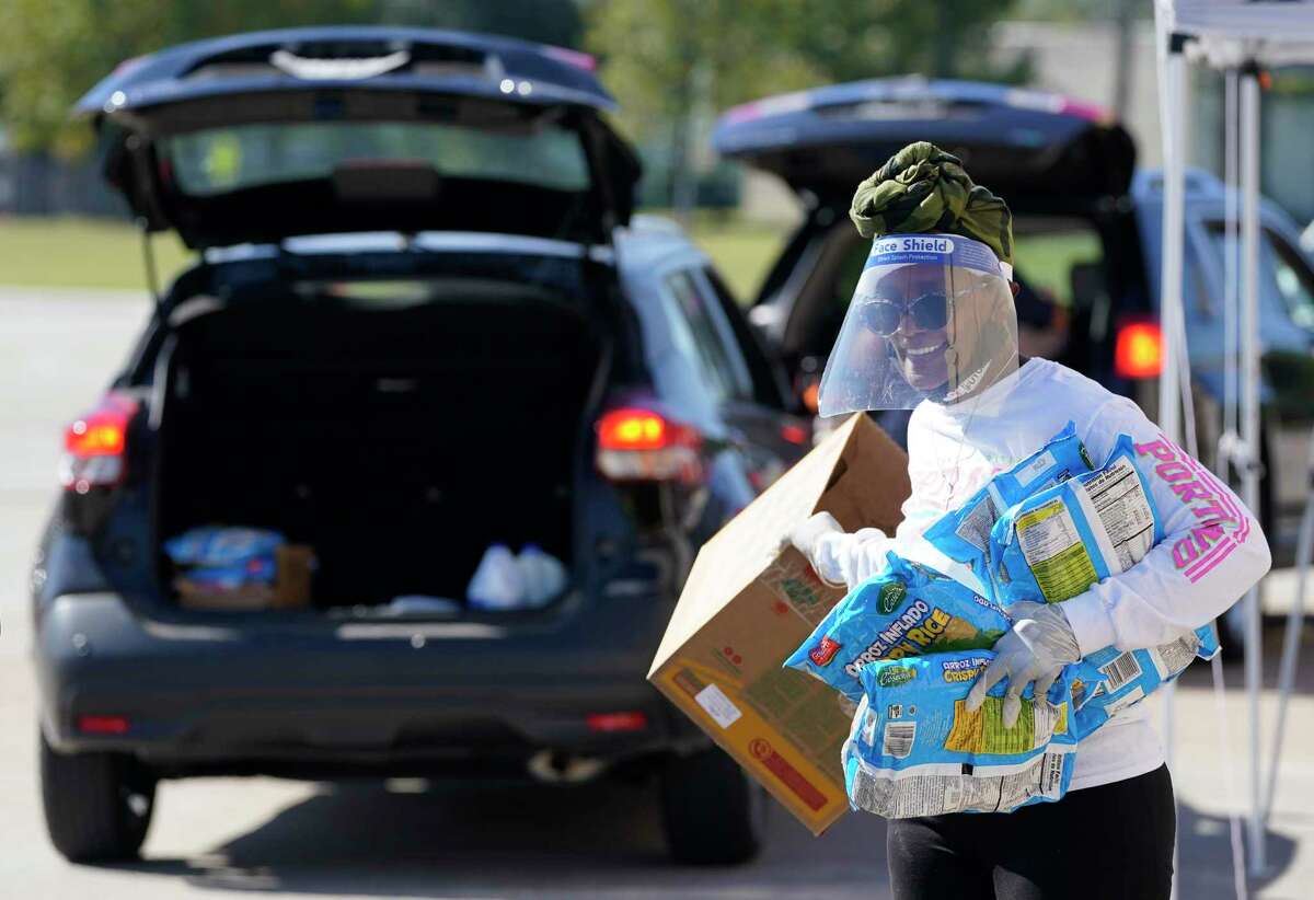 Linda Prescott carries bags of cereal to a vehicle during a food give away held at The Community of Faith, 1024 Pinemont Drive, Wednesday, Nov. 18, 2020 in Houston. The Community of Faith, Houston Black Real Estate Association, and BBVA will be hosting a food drive to collect non-perishable items on Saturday at the church from 10 am to 2 pm.