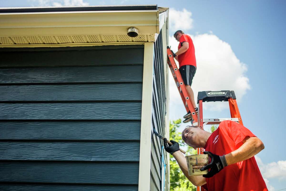 Volunteers paint siding on a home as part of the Midland County Habitat for Humanity's Neighborhood Revitalization Initiative on Wednesday, Aug. 7, 2019. (Katy Kildee/kkildee@mdn.net)