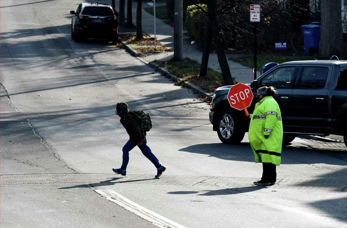 A William S. Hackett Middle School student makes a dash across Delaware Avenue after dismissal on Thursday, Nov. 19, 2020, in Albany, N.Y. The city of Albany is telling teachers to be prepared to go remote by Monday amid a surge in recent coronavirus cases throughout the Capital Region. (Will Waldron/Times Union)