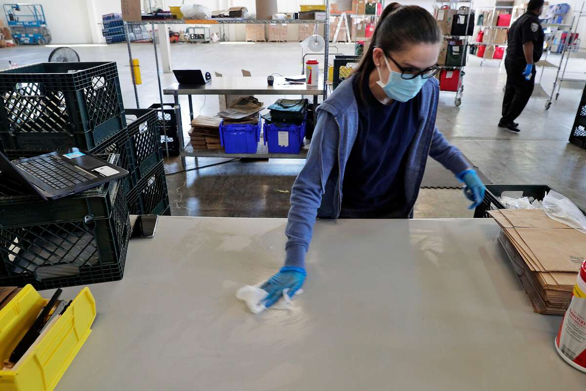 Doreen Rafas disinfects a workspace at the Farmstead Online Grocery warehouse in Burlingame, Calif., on Tuesday, August 11, 2020.
