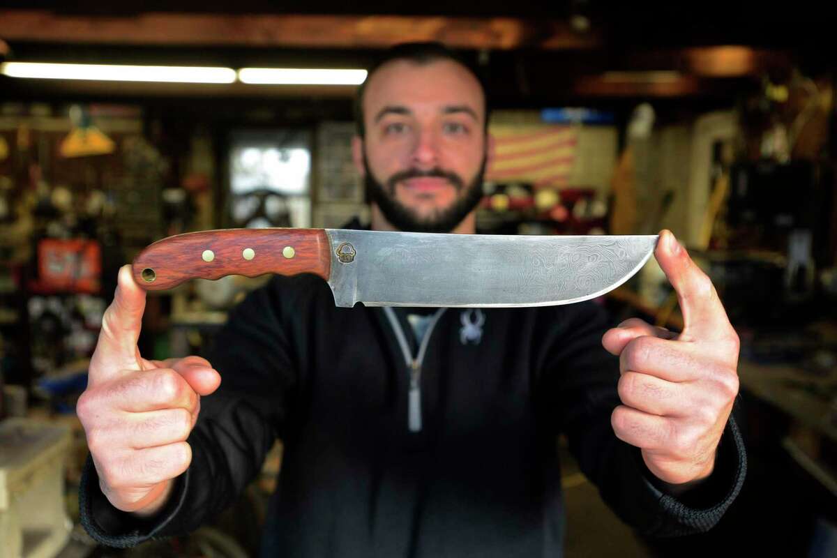 Mike Rizzo, of Danbury, who was featured on the TV show "Forged in Fire", holds up an everyday carry knife he made with a Damascus Blade. The blade is made from 144 layers of steel.Thursday, November 19, 2020, in Danbury, Conn.