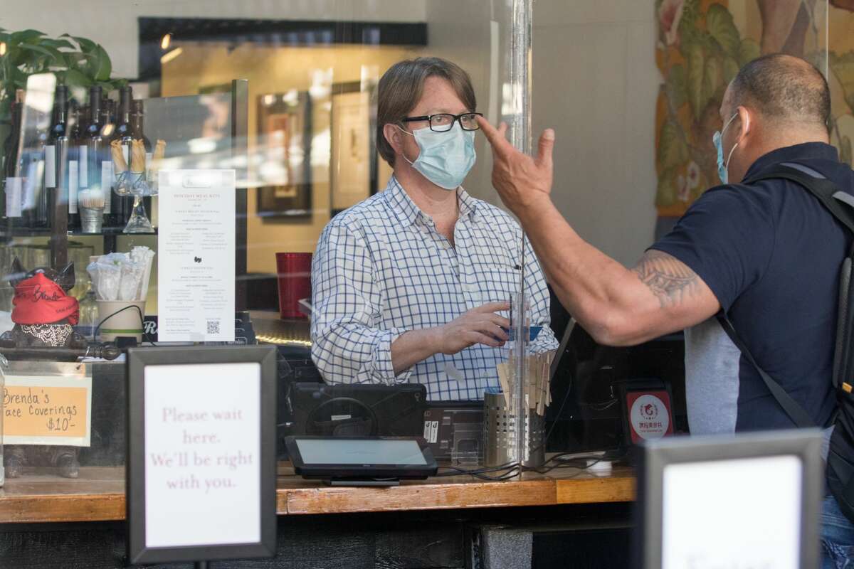 General Manager Hunter Alexander handles an order behind a sneeze guard at Brenda's Meat and Three on Divisadero Street in San Francisco on Nov. 19, 2020. Like many other restaurants, Brenda's has been severely affected by the COVID-19 coronavirus pandemic.