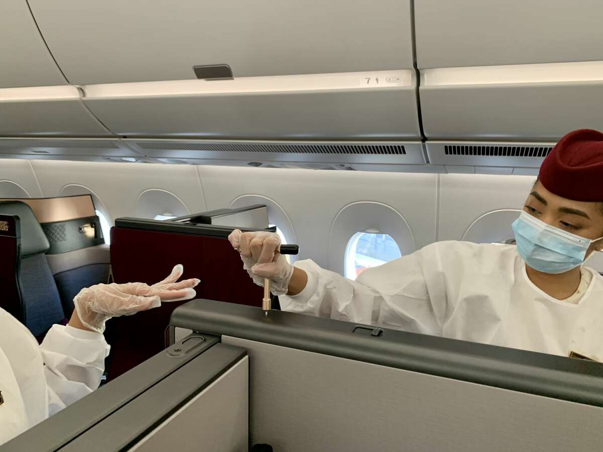 Flight attendants crank the special gold key that transforms seats into double beds on a Qatar Airways Airbus A350 similar to the one that will fly between San Francisco and Doha.