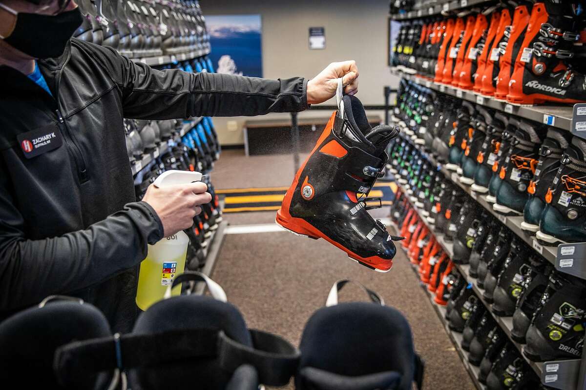 Zachary Kordal sprays disinfectant on rental ski boots during opening day at Heavenly Mountain Resort in South Lake Tahoe, California, November 20, 2020.