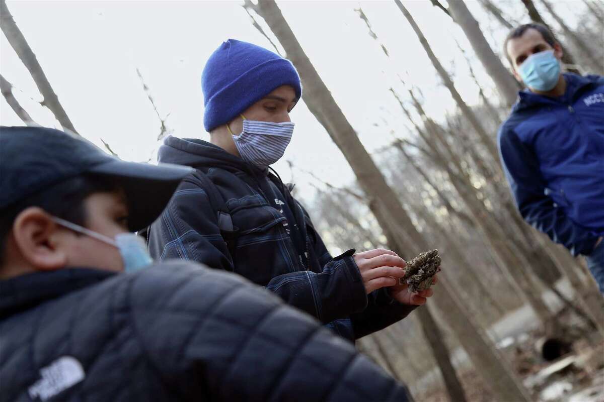 Sam Nunes talks about a piece of a wasp's nest found on the trail at Woodcock Nature Center at the sunset hike on Thursday.