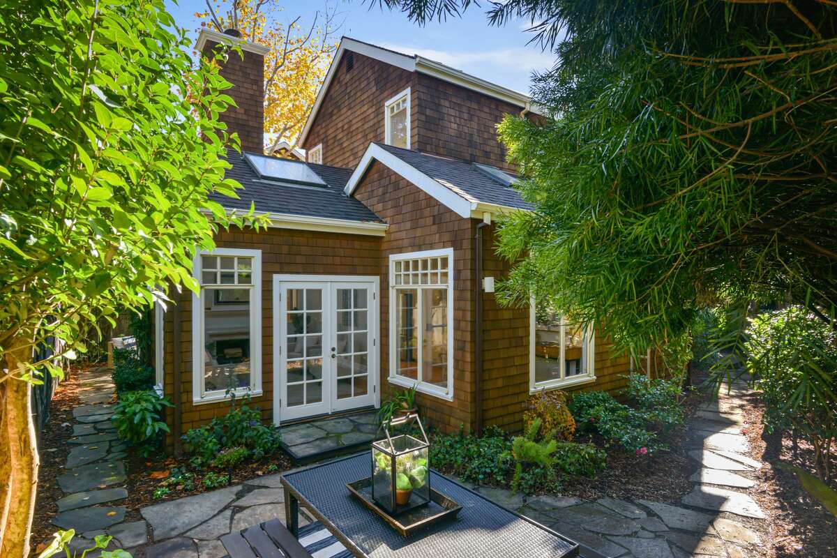 The home is tucked back on the lot, with a patio, gardens and trees. 