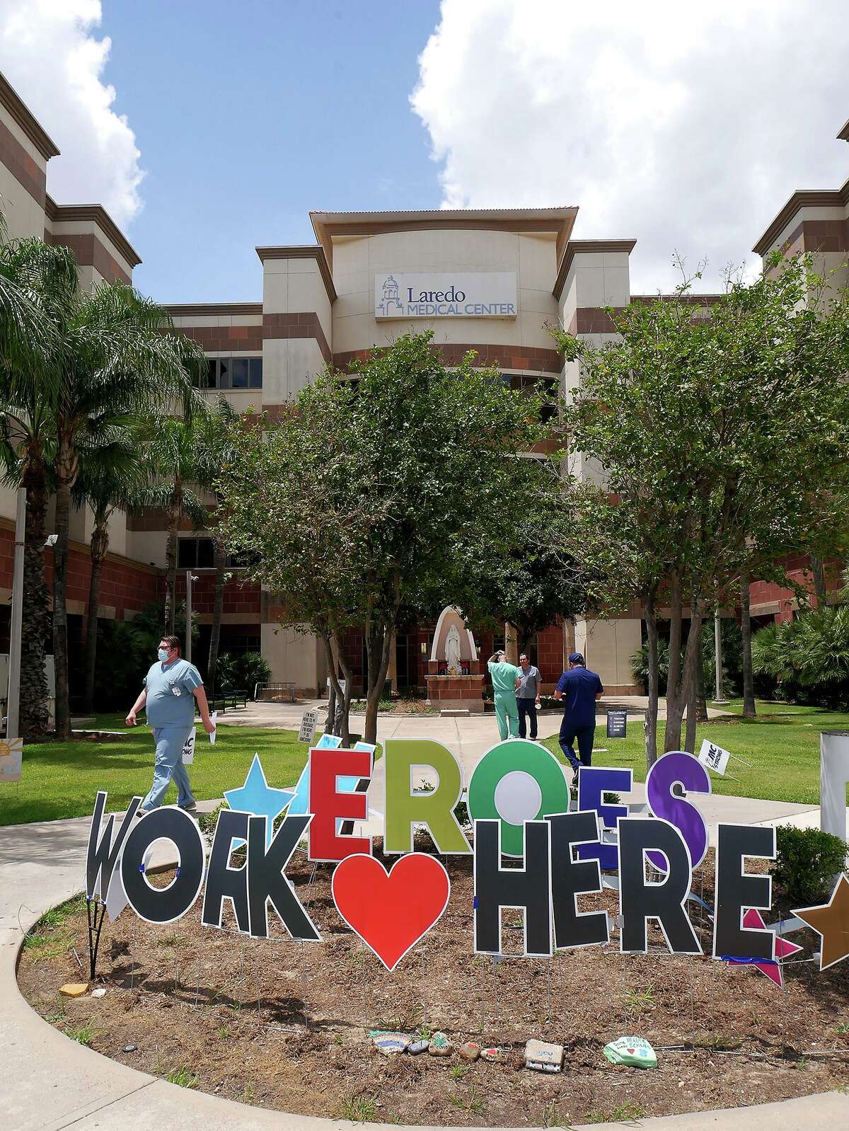 A “Heroes Work Here” sign sits outside Laredo Medical Center on May 11, 2020 as workers walk in and out of the facility. Recently, some recently departed staff discussed why many are leaving the area in favor of state positions, which they describe as having more pay and less stress.