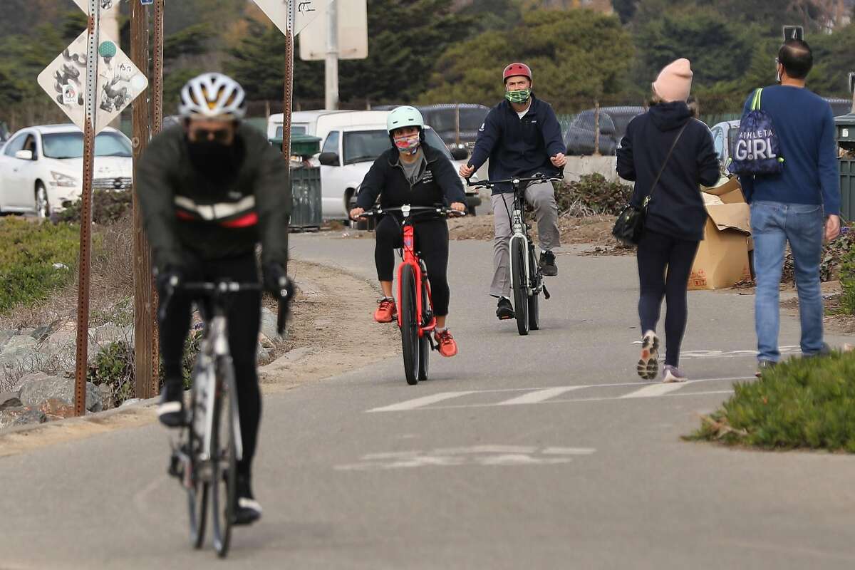 骑自行车的人沿着埃默里维尔的前边路利用星期六的宜人条件。