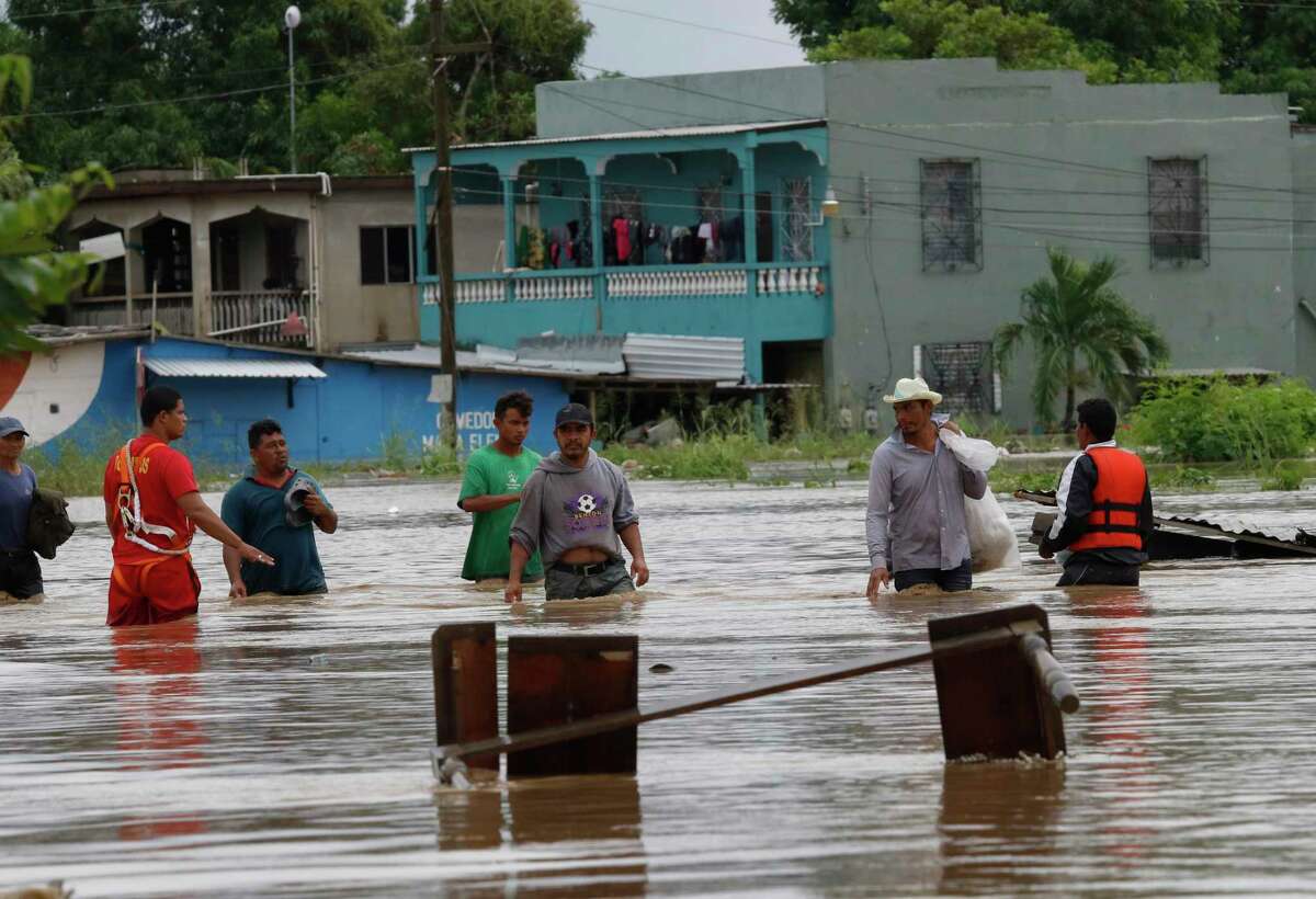 Men wade through a street flooded after the passing of Hurricane Iota in La Lima, Honduras, Wednesday, Nov. 18, 2020. Hurricane Iota was the strongest storm at landfall in the 2020 Atlantic hurricane season. Its center came ashore in northeast Nicaragua on Nov. 16 as a Category 4 hurricane with sustained winds near 155 mph (AP Photo/Delmer Martinez)