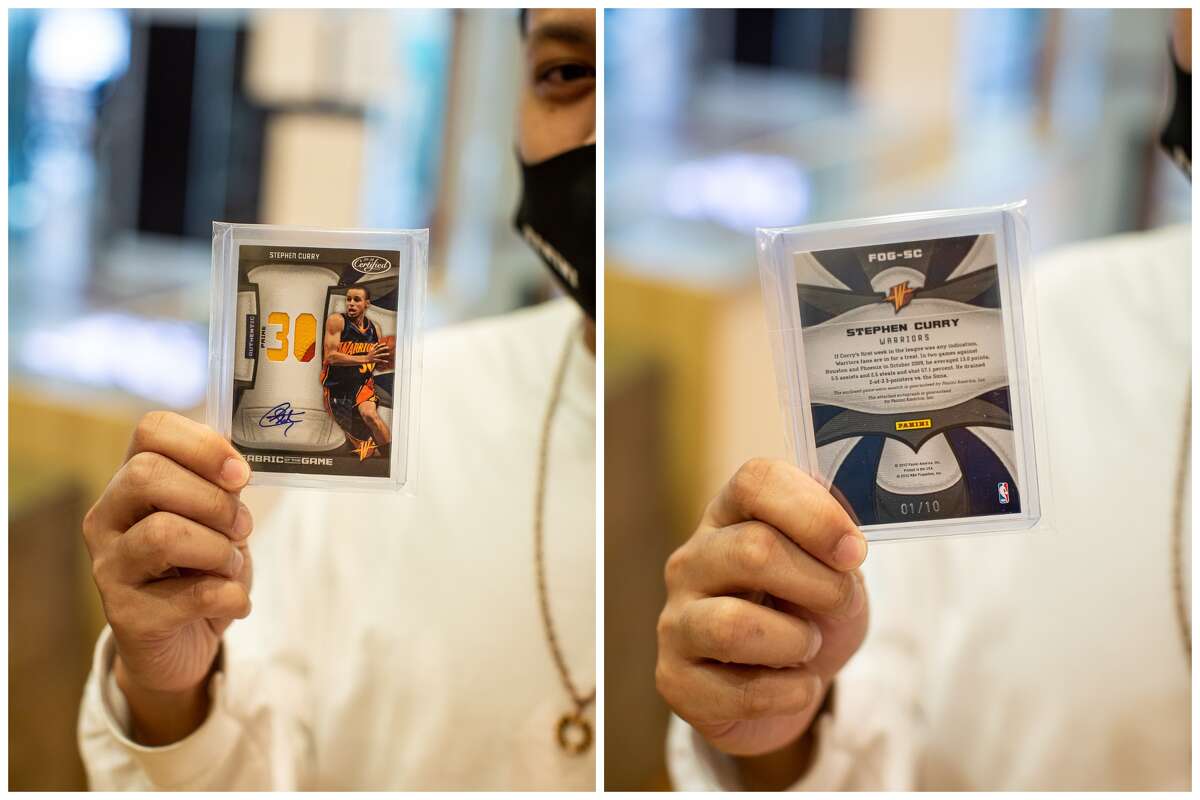 Classic Materials Sports & Collectibles store owner Rey Reyes holds up a Stephen Curry trading card.