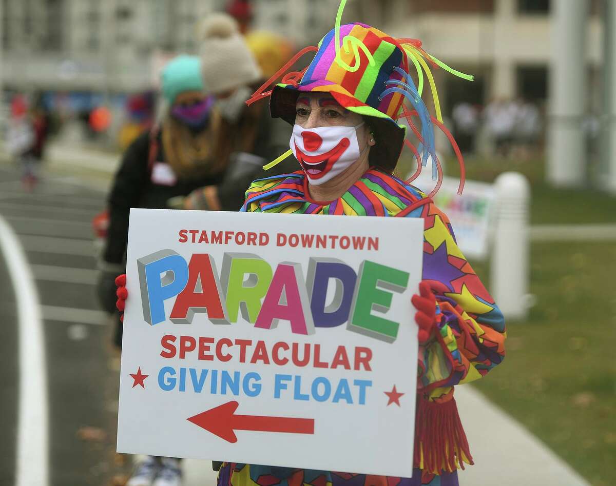 Clown Michele Carlucci, of Stamford, welcomes cars to the Stamford Downtown Parade Spectacular Giving Float turkey giveaway on Bedford Street in Stamford, Conn. on Sunday, Nov. 22, 2020.
