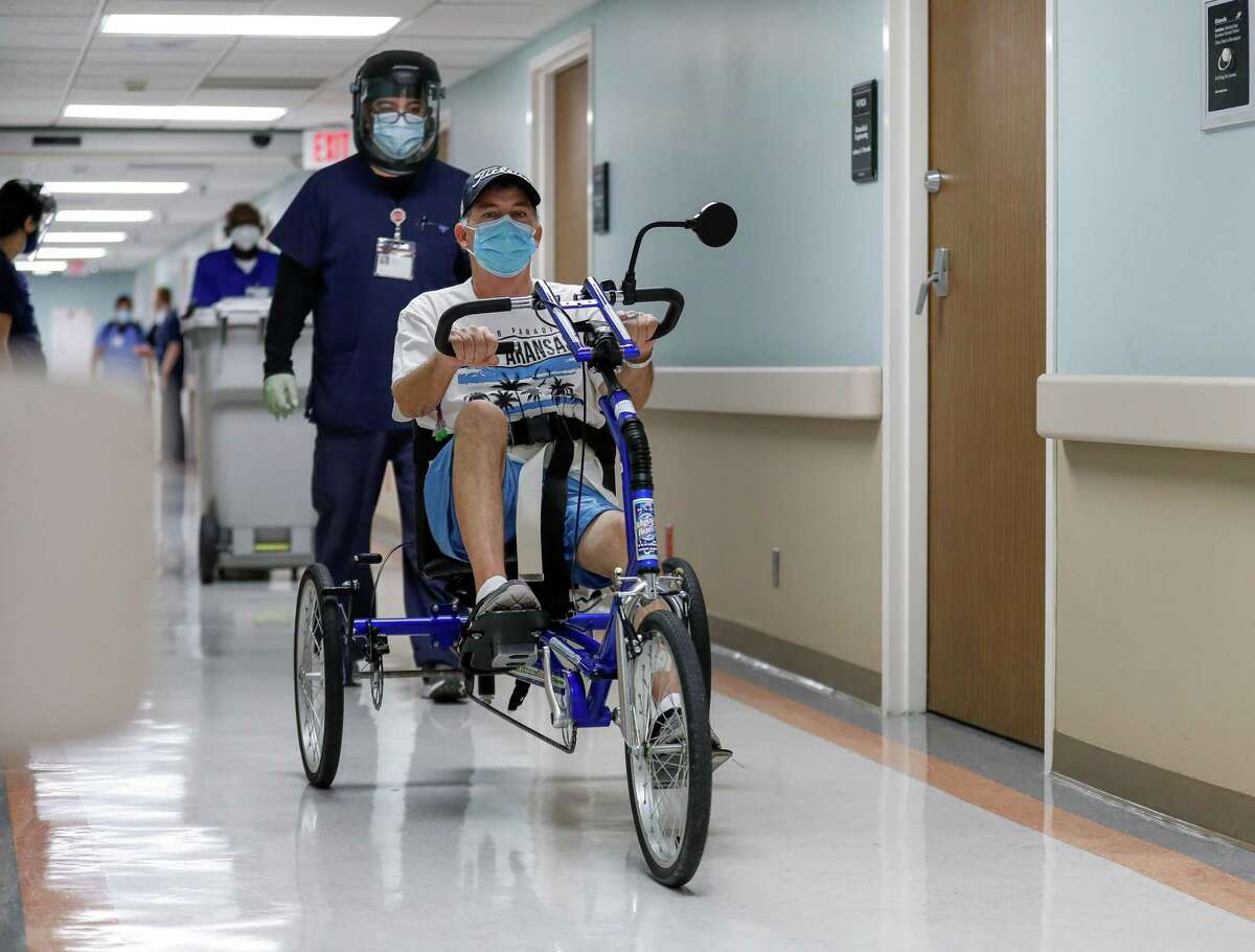 Thomas Steele uses a tricycle during his physical therapy session at Methodist Hospital on Friday, Nov. 20, 2020, in Houston. Steele, a healthy is recovering from spending two months on ECMO, and a double lung transplant, after getting COVID-19 this summer.
