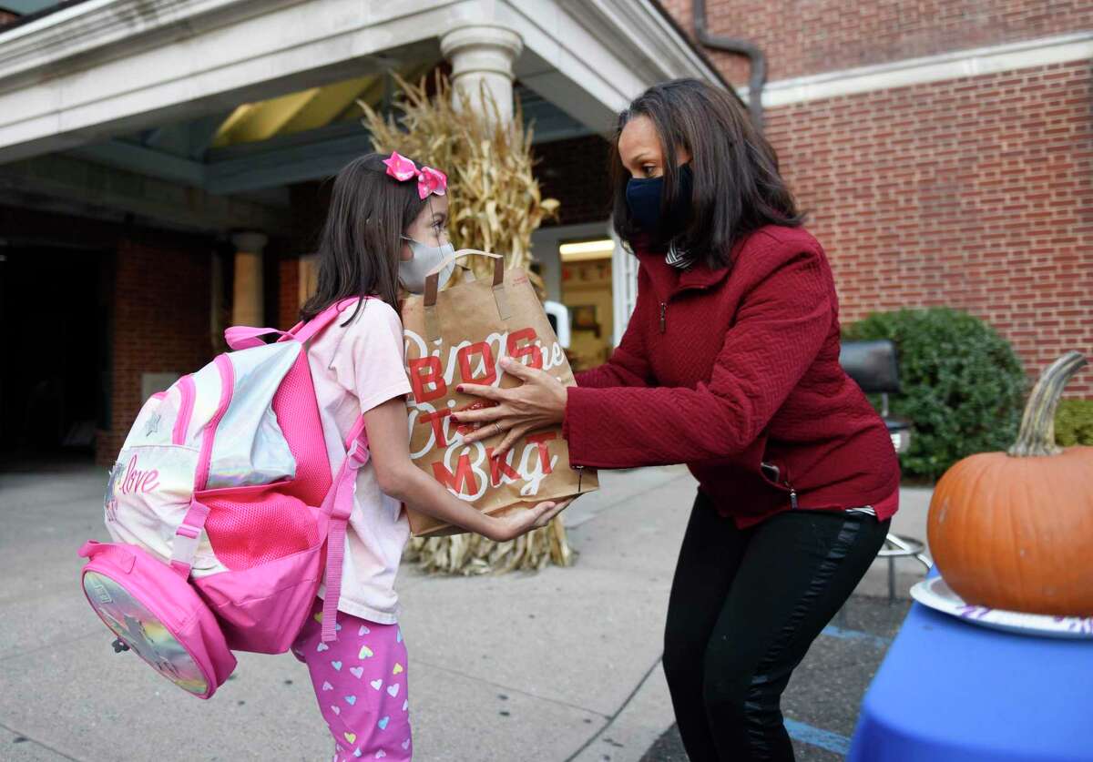 Breanna Da Mata, 9, accepts a Thanksgiving dinner for her family from Boys & Girls Club of Greenwich board member Iris Rivera during the Thanksgiving meal distribution at the Boys & Girls Club in Greenwich, Conn. Tuesday, Nov. 24, 2020. Instead of the usual buffet-style dinner for club kids, this year the Boys & Girls Club handed out Thanksgiving dinners fit to feed a family of six. More than 100 club families were fed full Thanksgiving meals of a rotisserie chicken, cornbread, stuffing, mashed potatoes, pies, and sparkling wine.