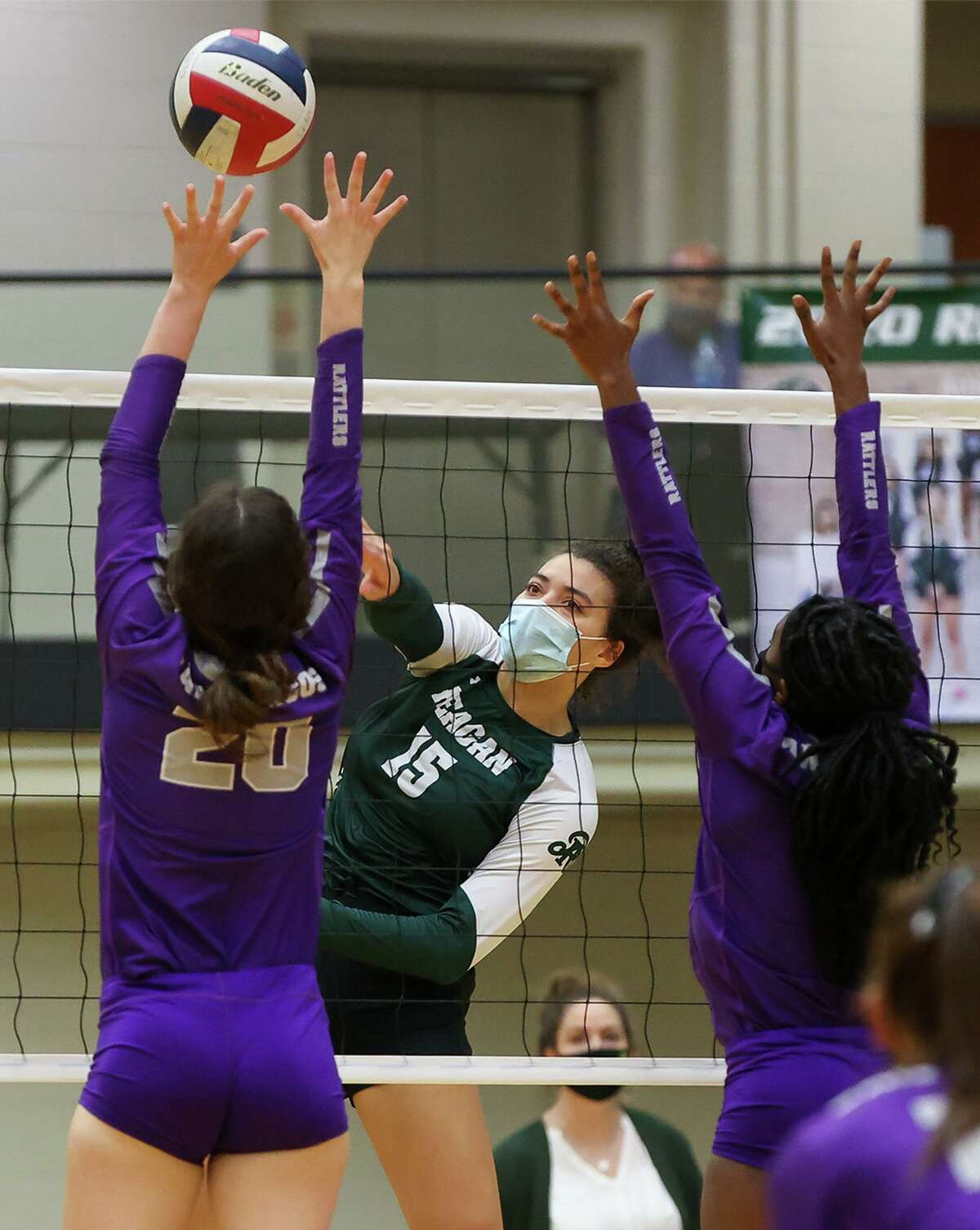 Reagan's Nyah Anderson, center, goes for a kill shot past San Marcos' Samantha Booth, left, and Qiera Green during their Class 6A volleyball second-round playoff match with San Marcos at Littleton Gym on Tuesday, Nov. 23, 2020. Reagan won the match in three sets: 25-20, 25-13, 25-12.