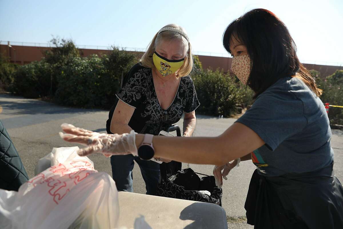 Volunteer Kim Langworthy (right), of San Francisco, assists Vicky Furlong (left) of San Francisco place bags of food into a car at the San Francisco-Marin Food Bank pop-up food pantry at Denman Middle School on Wednesday, October 28, 2020 in San Francisco, Calif.