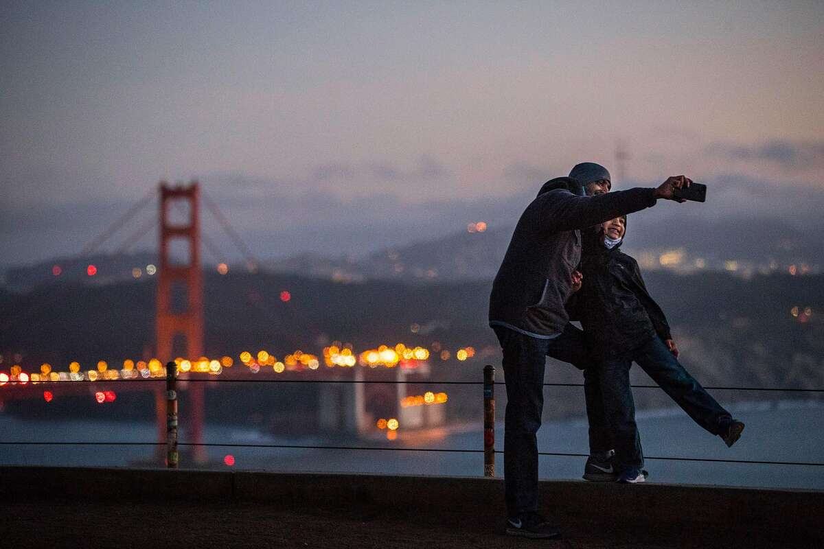 Maneesh Kenia, and his son Evy, 6, of Dublin take a photo in the Marin Headlands. Californians are taking short trips, but the tourist industry is suffering badly.