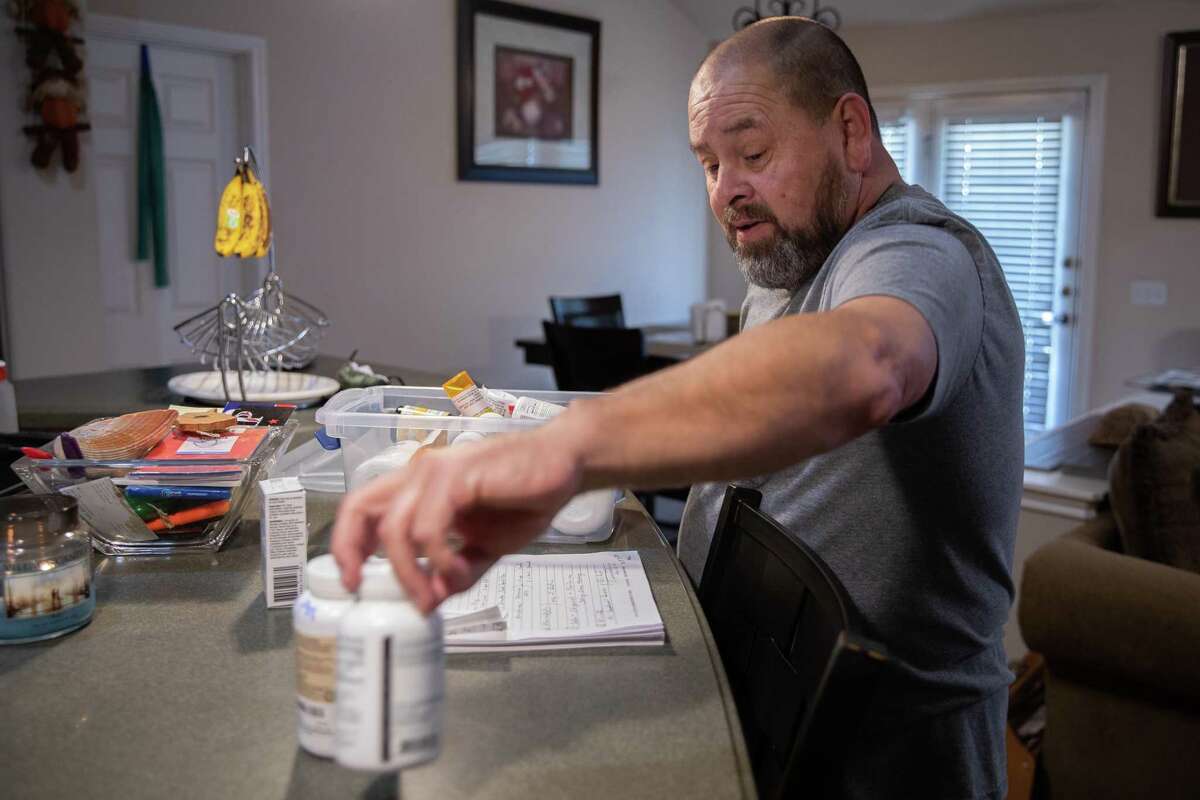 Ivy Jay Arroyo looks through his medications at his home in Pflugerville on Nov. 2. Arroyo caught COVID-19 in March and spent weeks at Baylor Scott & White Medical Center in Temple, near death and isolated from his family. After discharge, Arroyo was transferred by ambulance to a rehabilitation facility in Round Rock and was billed close to three times what his insurance paid for the ride.