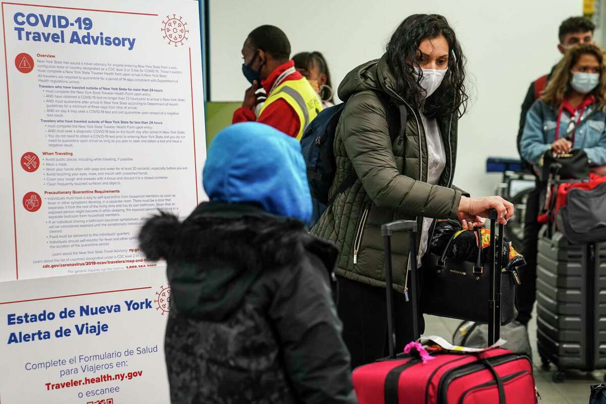 Varias personas portan mascarillas para evitar la propagación del COVID-19 mientras se preparan para abandonar la zona de entrega de equipaje en el Aeropuerto LaGuardia, el miércoles 25 de noviembre de 2020, en Nueva York.